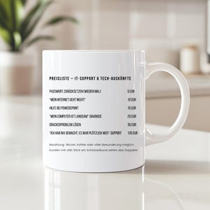 Könnte beinhalten: Weißer Keramikbecher mit gebogenem Henkel, mit schwarzem Text in deutscher Sprache. Der Text listet IT-Support-Dienstleistungen und Preise in Euro auf. Der Becher steht auf einer hellen Oberfläche, mit unscharfem Hintergrund.