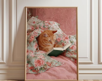 May include: A framed print of a ginger cat reading a book in bed. The cat is nestled under a floral blanket with pink and green hues. The book has a green cover. The background is a soft pink.