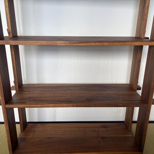 Peut inclure: Une &eacute;tag&egrave;re en bois avec trois tablettes. Les tablettes sont en bois brun fonc&eacute; et sont soutenues par des poutres verticales en bois.