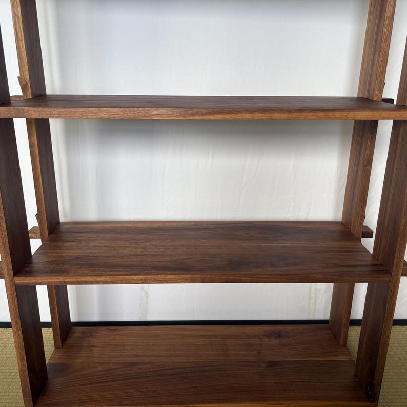 Peut inclure: Une &eacute;tag&egrave;re en bois avec trois tablettes. Les tablettes sont en bois brun fonc&eacute; et sont soutenues par des poutres verticales en bois.