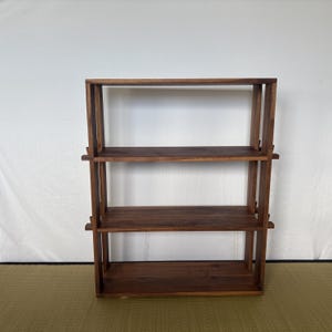 Peut inclure: Une &eacute;tag&egrave;re en bois &agrave; trois niveaux en bois de noyer fonc&eacute;. L'&eacute;tag&egrave;re a un design simple et minimaliste sans quincaillerie visible.