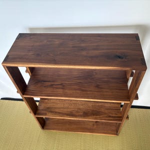 Peut inclure: Une &eacute;tag&egrave;re en bois brun fonc&eacute; avec trois &eacute;tag&egrave;res. Les &eacute;tag&egrave;res sont en bois massif et ont une finition naturelle. L'&eacute;tag&egrave;re est autoportante et a un design simple et moderne.