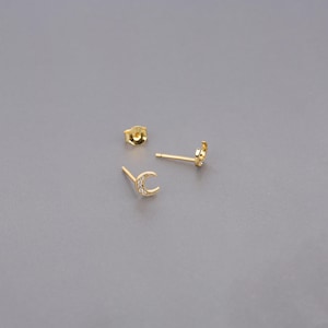 May include: A pair of gold crescent moon earrings with small clear stones set into the crescent shape.