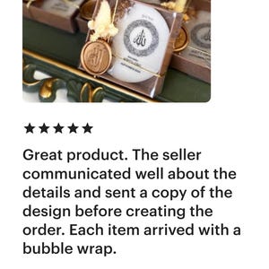 May include: A selection of white, round soaps in transparent boxes, each with a gold seal and decorative elements. The soaps feature a circular design with Arabic script. The boxes are on a green surface.