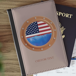 以下が含まれることがあります： アメリカ国旗と青い海を描いた、丸窓デザインのパスポートケース。ベージュ色のケースには「CUSTOM TEXT」の文字がプリントされています。パスポート、航空券、車のキーも写っています。