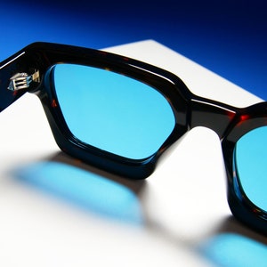 Puede incluir: Gafas de sol de carey con lentes azules. Las gafas est&aacute;n dobladas por la mitad y el interior de la montura es visible. La montura tiene el texto "45 C2 CE" en ella.