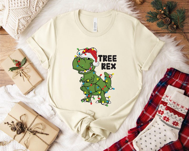 a white t - shirt with a green dinosaur wearing a santa hat