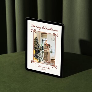 Puede incluir: Una tarjeta de Navidad digital con una foto de una familia de pie frente a un &aacute;rbol de Navidad decorado. La tarjeta tiene un borde rojo con lazos y el texto "Feliz Navidad, los Daniels, 2021".