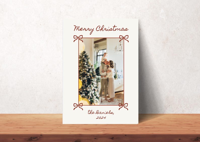 Puede incluir: Una tarjeta de Navidad con una foto de una familia de pie frente a un &aacute;rbol de Navidad decorado. La tarjeta tiene un dise&ntilde;o de lazo rojo y el texto "Feliz Navidad, los Danielo, 2024".