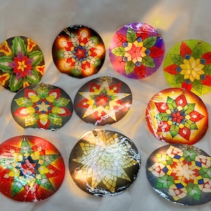 May include: A collection of ten colorful, round star-shaped ornaments. Each ornament features a unique geometric design with vibrant hues of red, yellow, green, and blue. The ornaments are illuminated, creating a warm glow.