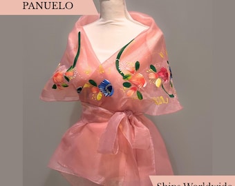 May include: A sheer, light pink Filipiniana panuelo shawl draped over a mannequin. The garment features hand-painted floral motifs in shades of blue, orange, and green, with a tie-waist closure. Text on the image reads FILIPINIANA PANUELO.