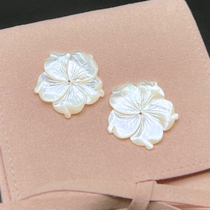 May include: Two white mother-of-pearl flower shaped buttons with a hole in the centre.