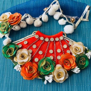 May include: A decorative, handcrafted item featuring a vibrant red fan-shaped piece adorned with sparkling rhinestones and colorful fabric roses in shades of orange, green, and gold. A blue fabric piece with white pom-poms is also present.