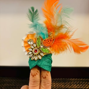 May include: A green, orange, and white turban with a jeweled flower and feathers.