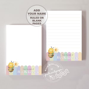 May include: Two rectangular notepads featuring a watercolor illustration of a smiling bee holding a daisy. The bottom border has pastel vertical stripes. The text reads, "from the desk of Mrs Robinson." One notepad is blank, and one is lined.