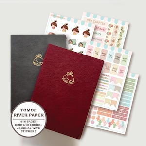 Puede incluir: Un cuaderno de cuadrícula gris oscuro y otro rojo intenso, ambos con un icono de línea dorada de una cabeza en la portada. El set incluye hojas de pegatinas coloridas con textos como "NEW CHAPTER", "THE DAY", "MAGIC" y una etiqueta "TOMOE RIVER PAPER 416 PAGES GRID NOTEBOOK / JOURNAL WITH STICKERS".