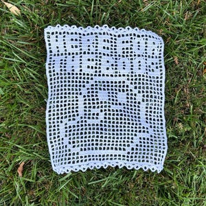 May include: A light blue crocheted doily with a scalloped edge. The doily is made with a delicate pattern and is perfect for adding a touch of elegance to any home.