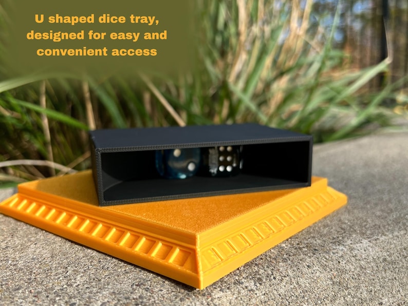 May include: A black U-shaped dice tray with a raised base. The tray is designed for easy and convenient access to dice. The tray is sitting on a yellow base with a decorative border.