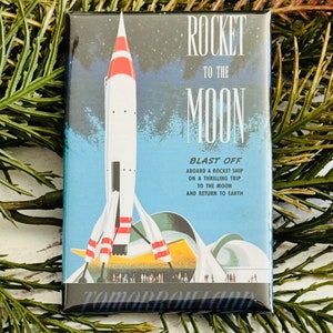 Peut inclure: Une illustration de style vintage d'une fusée décollant vers la lune. Le texte indique "Rocket to the Moon, Blast Off Aboard a Rocket Ship on a Thrilling Trip to the Moon and Return to Earth".