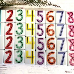 May include: A set of 36 white tiles with black numbers 1 through 8. Each number is repeated four times. The tiles are arranged in four rows of nine tiles.