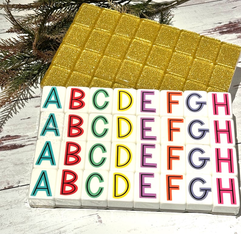 May include: A set of colorful alphabet tiles with letters A through H. Each tile is white with a black outline and a different color for each letter. The tiles are arranged in four rows of eight tiles.