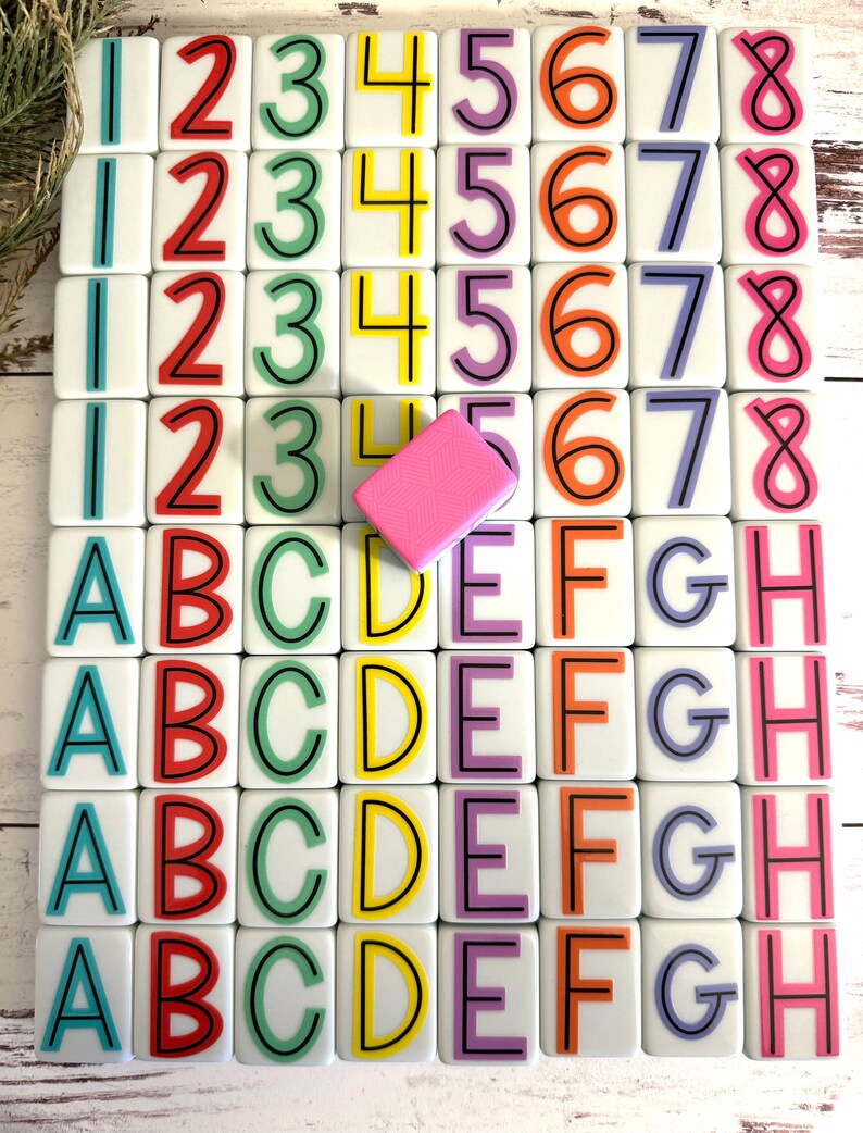 May include: A set of 36 white tiles with colorful numbers and letters. The tiles are arranged in four rows of nine. The numbers are 1 through 8 and the letters are A through H. The tiles are on a white wooden surface.