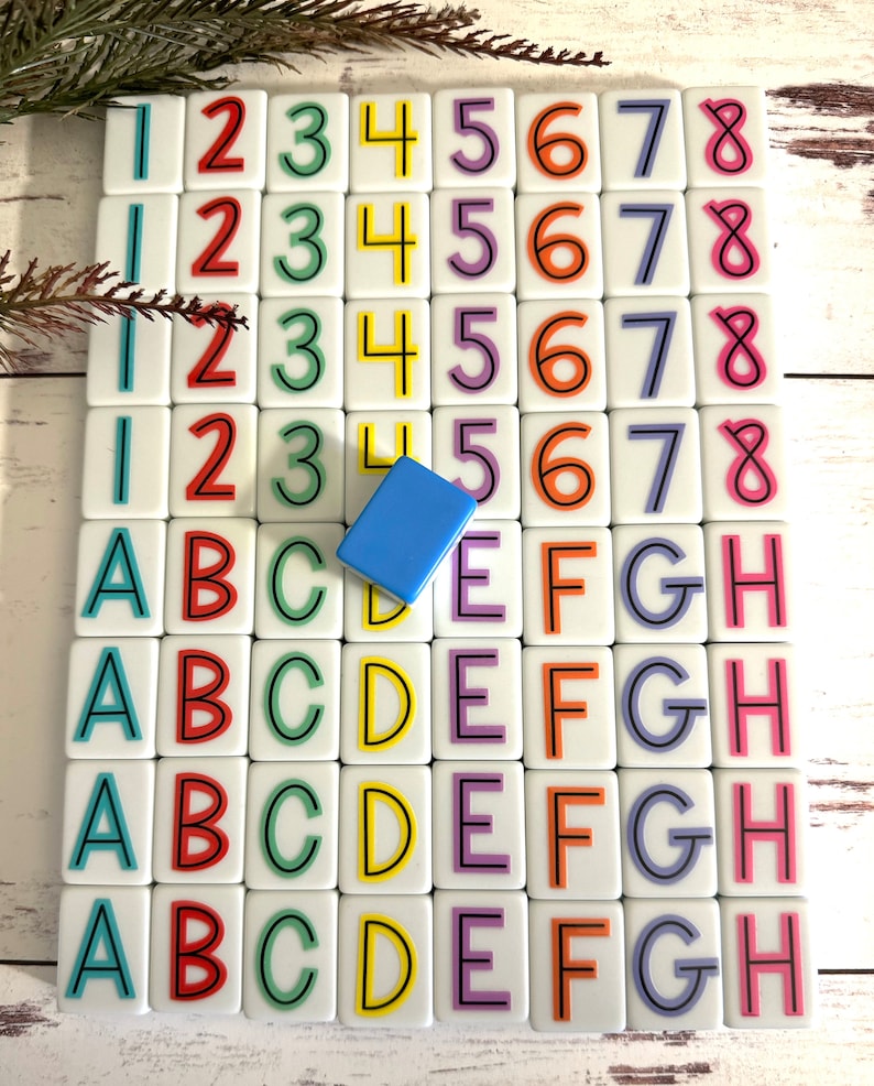 May include: A set of colorful tiles with numbers 1 through 8 and letters A through H. The tiles are arranged in a grid pattern on a white wooden surface. A blue tile is placed in the center of the grid.