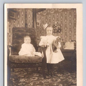 Intérieur antique AZO carte postale avec photo réelle, petite fille, grande soeur, ours en peluche, tapis en papier peint