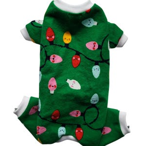 May include: Green dog pyjamas with a Christmas light pattern. The lights are red, yellow, pink, blue and white with smiling faces.