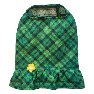 May include: Green plaid dog dress with a yellow flower accent. The dress has a ruffled bottom.