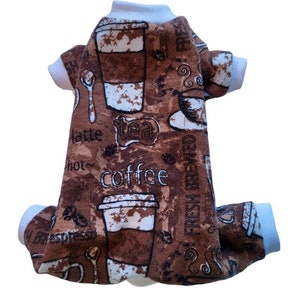 Peut inclure: Pyjama pour animaux de compagnie marron et blanc avec un motif sur le thème du café. Le tissu présente des tasses à café, des grains de café et les mots "coffee", "tea" et "fresh brewed". Le pyjama a des poignets blancs et un col blanc.