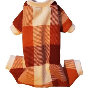 May include: Orange and white plaid dog pajamas with white trim around the neck and cuffs.