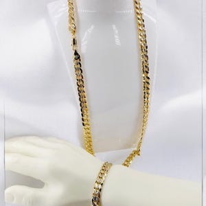 May include: A gold chain necklace and bracelet set with a curb link design. The necklace is displayed on a white mannequin bust and the bracelet is on a mannequin hand.