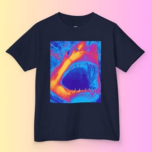 Op de afbeelding: Een marineblauw t-shirt met een afbeelding van een open haaienbek in een levendig oranje, blauw en paars kleurenschema.