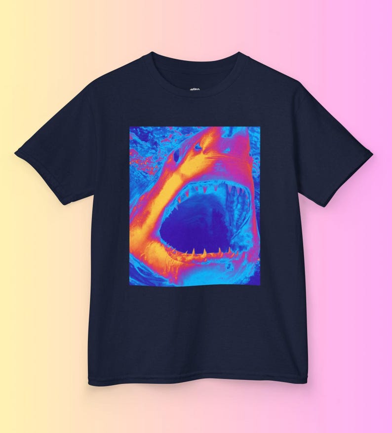 Op de afbeelding: Een marineblauw t-shirt met een afbeelding van een open haaienbek in een levendig oranje, blauw en paars kleurenschema.