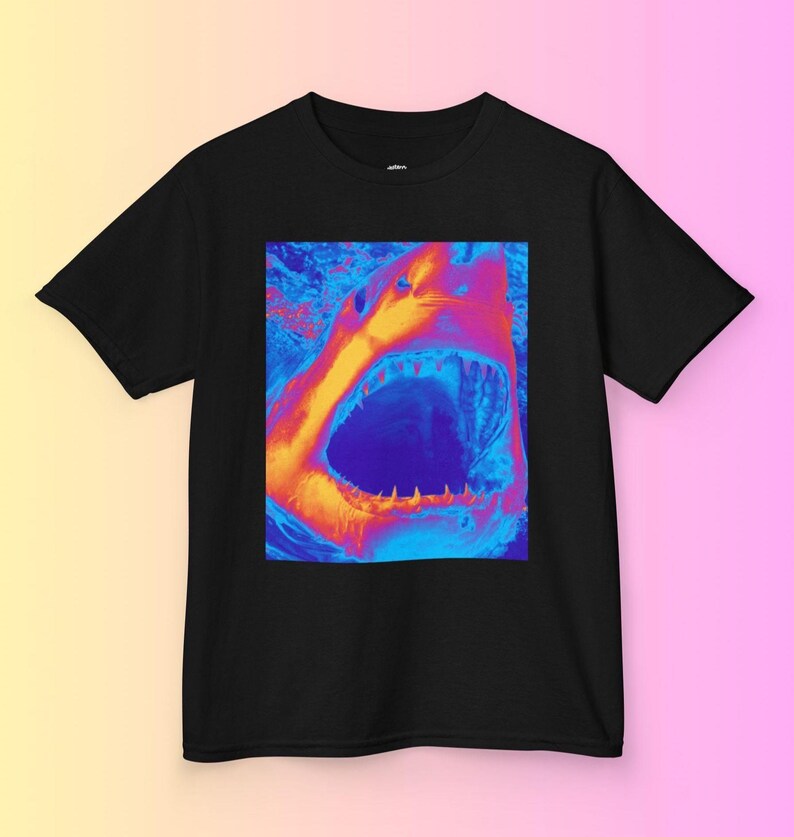 Op de afbeelding: Een zwart T-shirt met een afbeelding van een open haaienbek in een levendig, psychedelisch kleurenschema van oranje, blauw en paars.