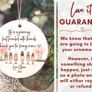 May include: A round white ceramic ornament featuring an illustration of six figures standing in a row among pink trees. The text reads: Life is a journey best traveled with friends. Thank you for being mine. Love, Olivia. 2026. A silver string is attached.