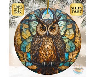 May include: A round Christmas ornament featuring a stained glass style owl with brown, yellow, and blue colors. The owl is perched on a branch with leaves.