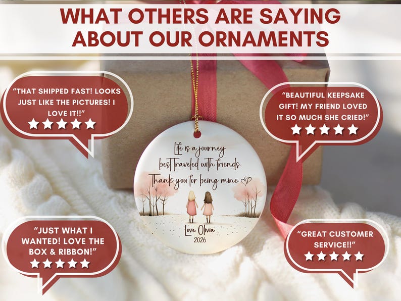 May include: A round white ceramic ornament featuring an illustration of two figures standing in a landscape with trees. The text reads: Life is a journey best traveled with friends. Thank you for being mine. Love, Olivia 2026. It hangs by a gold cord.