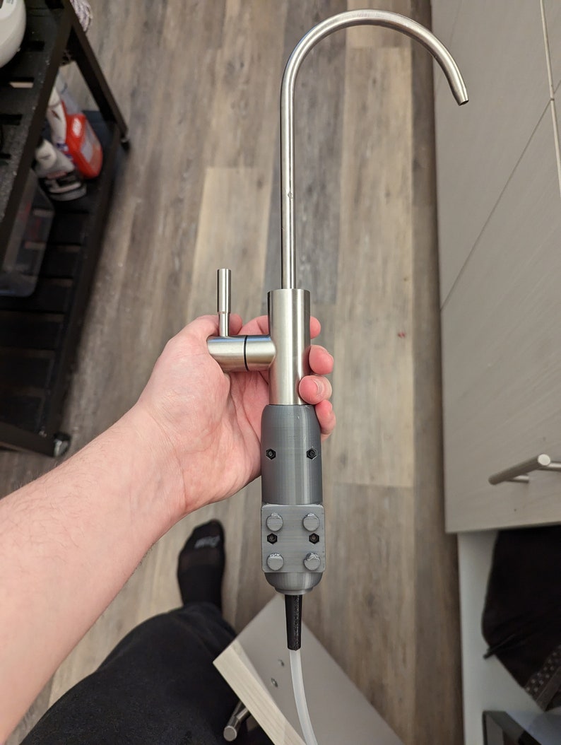 May include: A stainless steel kitchen faucet with a gray plastic adapter. The faucet has a single handle and a curved spout.