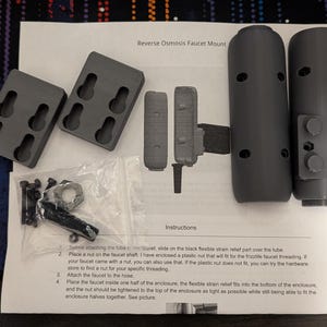 May include: Instructions for installing a reverse osmosis faucet mount. The kit includes two black plastic pieces, a nut, screws, and a strain relief part. The instructions include steps for attaching the faucet to the hose and securing the mount.
