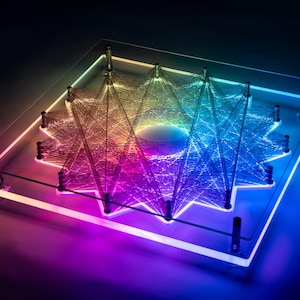 Può includere: Un'opera d'arte in filo con un design a stella e colori arcobaleno, montata su una base in acrilico trasparente.