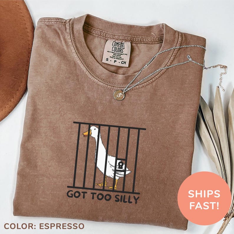a brown shirt with a duck in a cage on it