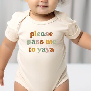 a baby wearing a bodysuit that says please pass me to yaya