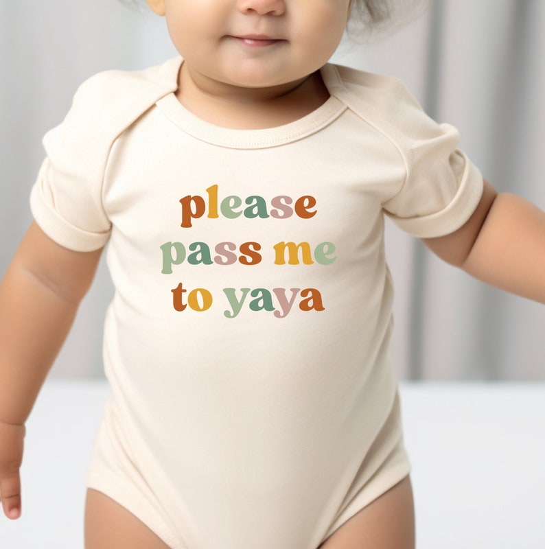 a baby wearing a bodysuit that says please pass me to yaya