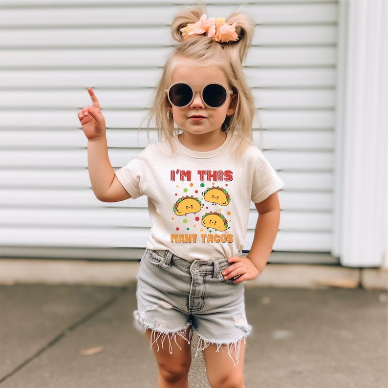 a little girl wearing sunglasses and a t - shirt that says i'm this