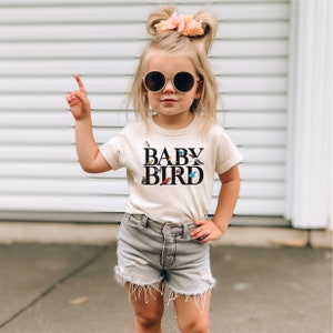 a little girl wearing a baby bird t - shirt