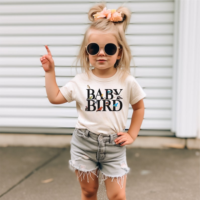 a little girl wearing a baby bird t - shirt