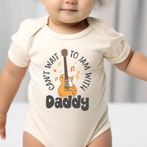 a baby wearing a bodysuit with a guitar on it