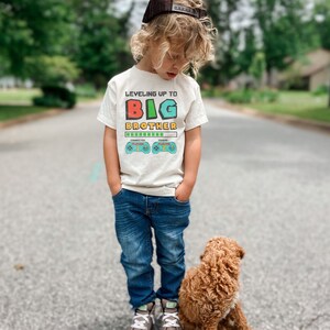 a little boy standing next to a brown dog